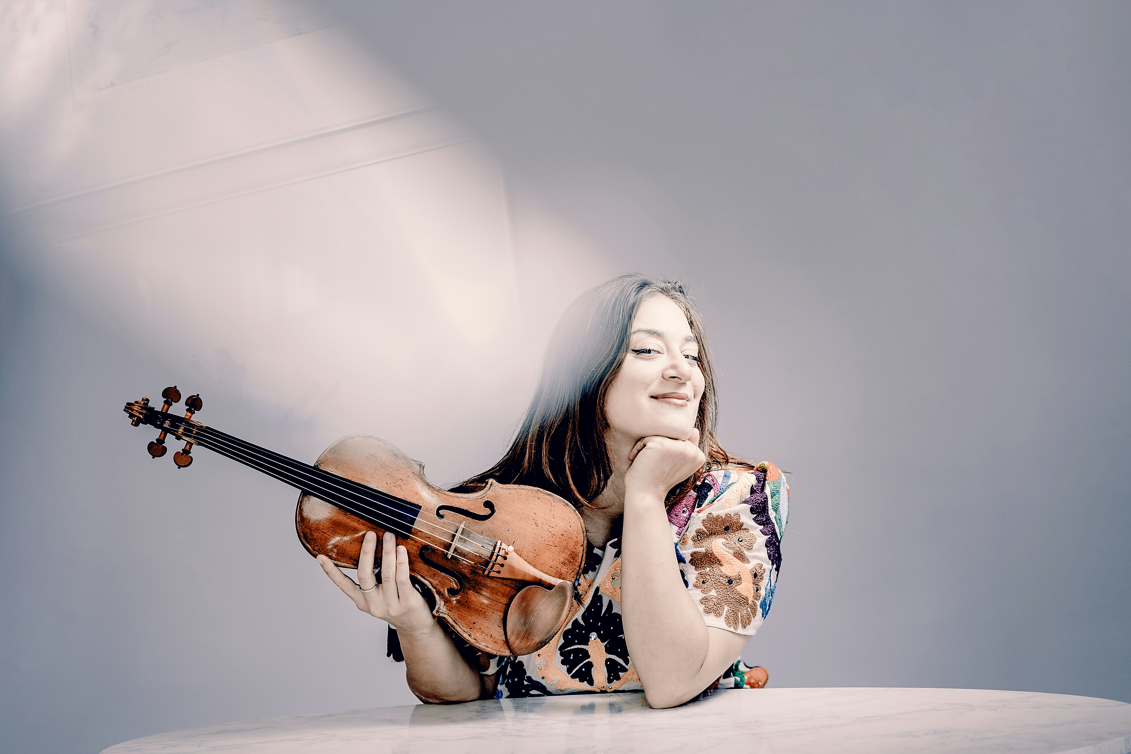 Veriko holding her violin at a table, photographed by Andrej Grilc